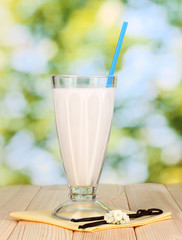 Vanilla milk shake on wooden table on bright background