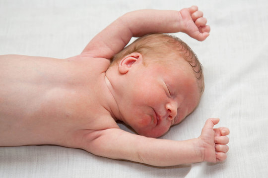 Peacefully and soundly sleeping naked newborn tiny slim baby