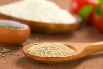 Active dry yeast on wooden spoon with oregano, flour