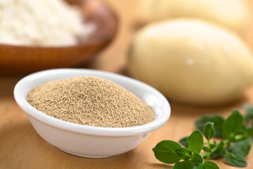 Active dry yeast in small bowl with fresh oregano