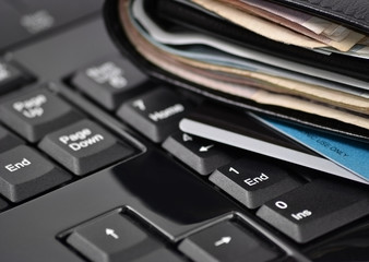 Wallet with money and bank cards on computer keyboard