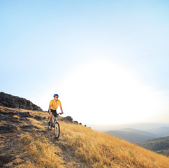 Young male riding a mountain bike on a sunset