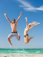 happy couple jumping on the beach