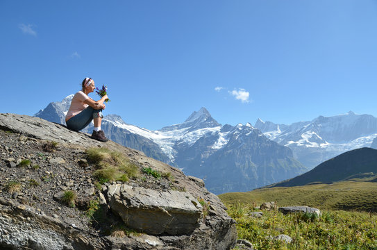 Girl sitting on a rock against Swiss Alps