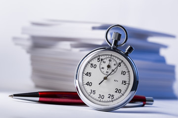 Stopwatch and pen on background of paper cards