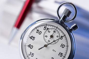 Stopwatch and pen on background of paper cards