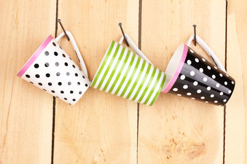 Obraz premium Nice cups hanging on nails on wooden background