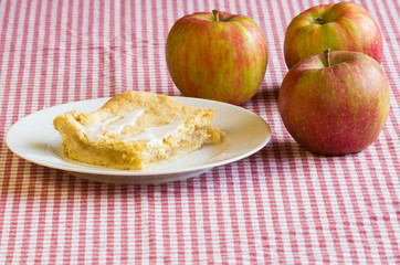 Apple pie on white plate with apples