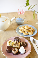 plates of pastries and biscuits and tea pot on wooden table