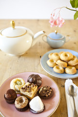 Obraz na płótnie Canvas talerze ciast i herbatników i czajniczka na drewnianym stole
