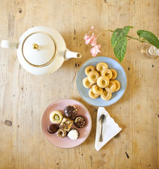 plates of pastries and biscuits and tea pot on wooden table