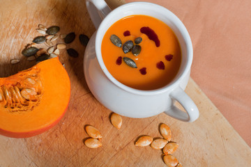 Pumpkin vegetable cream soup in white bowl with pumpkin