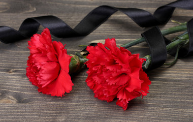 carnations and black ribbon on grey wooden background