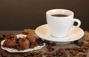 Cup of coffee on wooden table on brown background