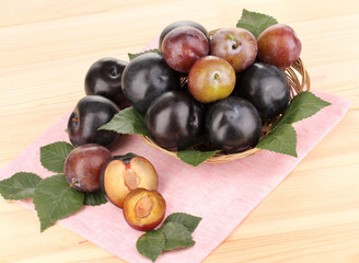 Rip plums on basket on wooden table