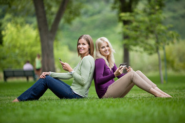 Female Friends With Cellphones In Park