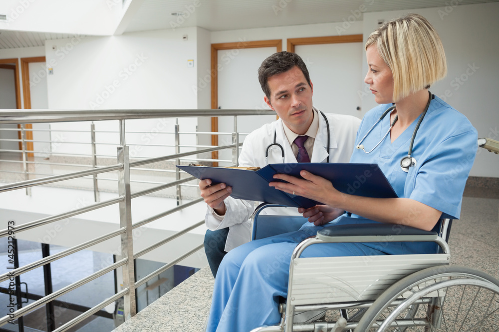 Wall mural Doctor and nurse in wheelchair studying folder