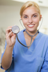 Smiling nurse holding up a stethoscope