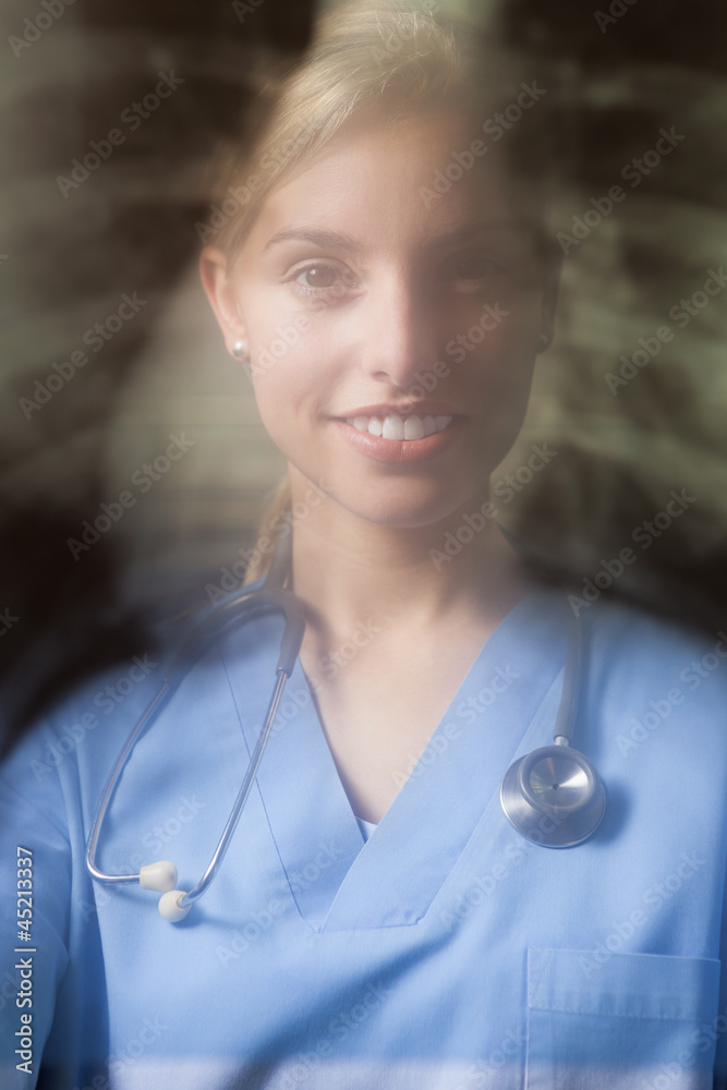 Wall mural Young female doctor with blurred x-ray background