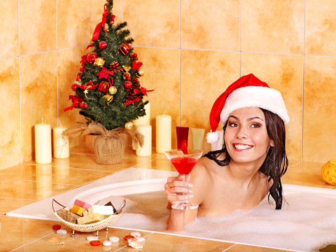 Woman in santa hat relax in bath.