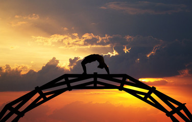 silhouette of gymnast on bridge in sunset