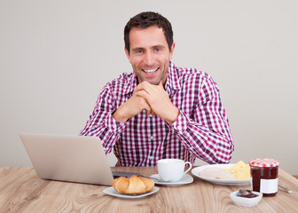 Portrait Of Young Man Using Laptop At Breakfast