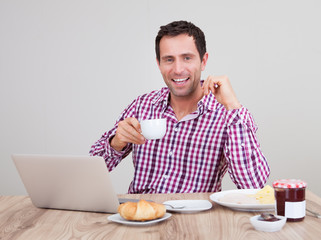 Portrait Of Young Man Using Laptop At Breakfast