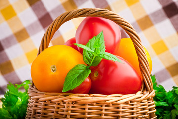 Wicker basket full of fresh tomatoes and cherry tomatoes