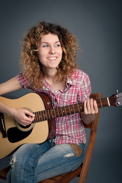 Smiling country girl with a guitar singing.