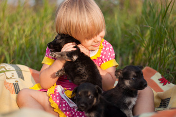 Naklejka na ściany i meble Little girl playing with puppies