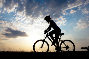 Biker-girl at the sunset on the meadow