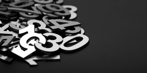 closeup image with pile metal numbers on black background