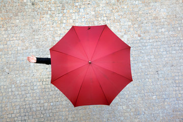 Business woman hidden under umbrella and checking if it's rainin