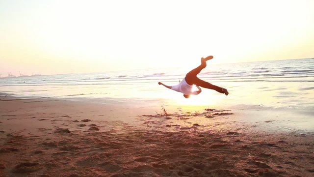 Jeune homme dansant sur la plage