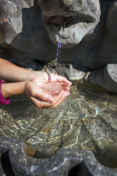 Hands collecting water from fountain