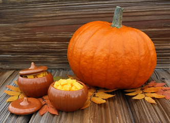 Big pumpkin and pottery with pumpkin slices on a wooden backgrou