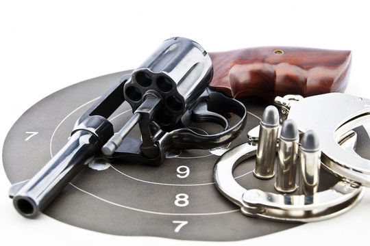 handgun revolver and police handcuff with bullets on white backg