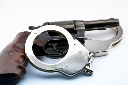 handgun revolver and police handcuff on white background