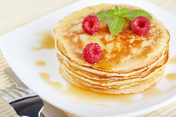 Pancakes with honey, raspberry and a mint branch