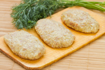Raw meatballs with dill on breadboard