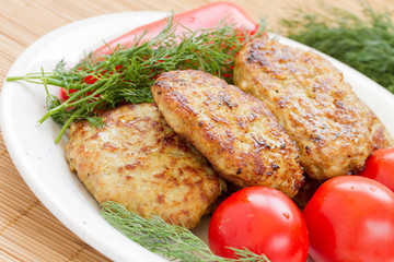 Fried meatballs with dill and tomatoes on a plate