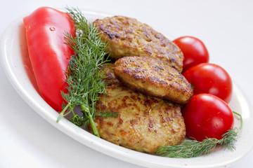 Fried meatballs with dill and tomatoes on a plate
