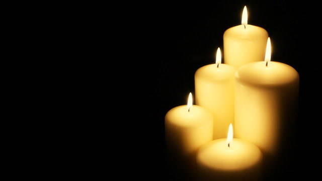 Five flickering candles on the black background