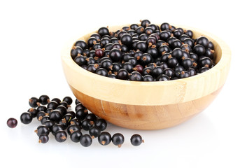 Black currant in wooden bowl isolated on white