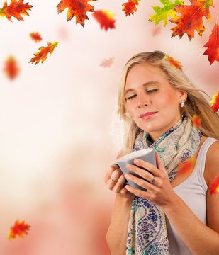 Conceptual autumn portrait of beautiful blond woman drinking tea