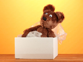 Opened parcel with a child's toy on yellow background close-up