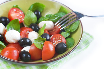 Salad with tomatoes, mozarella, olives and basil