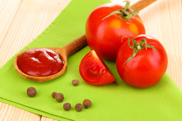 Ketchup and ripe tomatoes on wooden table