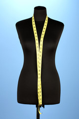 empty black mannequin with measuring tape  on blue background