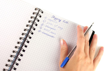 woman's hand holding a notebook with a shopping list close-up